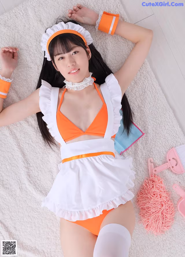 A woman in an orange and white maid outfit laying on a bed.