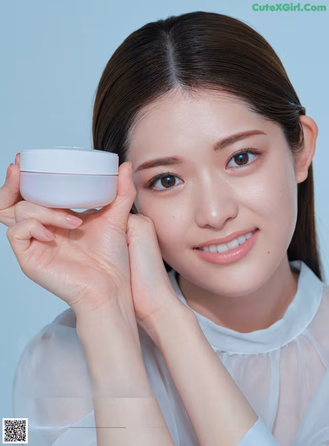 A woman holding a jar of cream in her hand.
