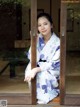 A woman in a kimono leaning against a wooden door.