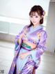 A woman in a purple and blue kimono posing for a picture.