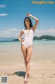 A woman in a white swimsuit standing on a beach.