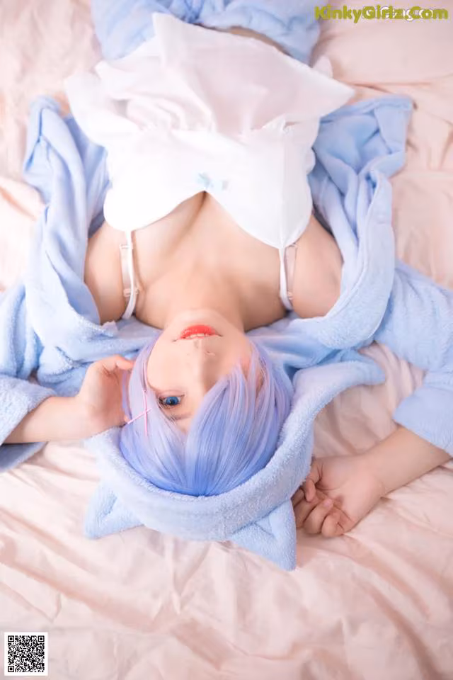 A woman laying on a bed in a blue robe.