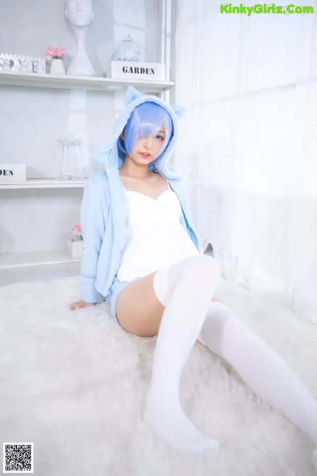 A woman in a blue cat costume sitting on a white rug.