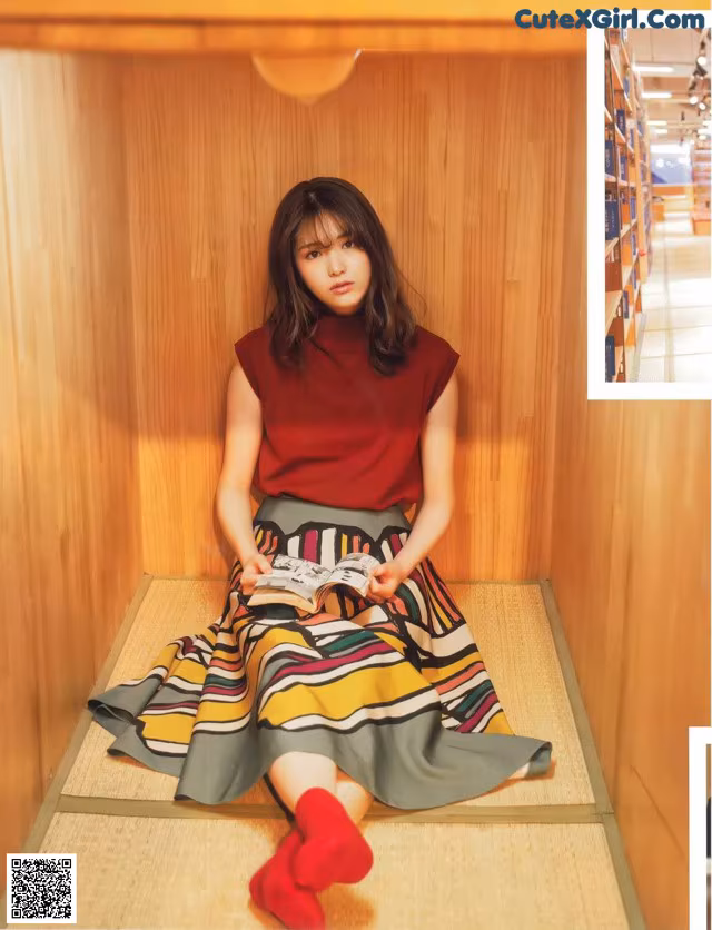A woman sitting on a bench reading a book.