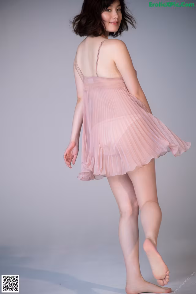 A woman in a pink dress is posing for a picture.