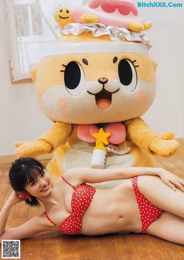 A woman in a red bikini laying on the floor next to a giant stuffed animal.