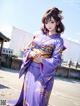 A woman in a purple kimono standing on a beach.