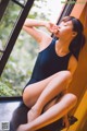 A woman in a black leotard sitting on a window sill.