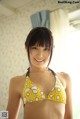 A woman in a yellow and white bikini posing for a picture.