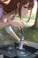 A girl is pouring water into a fountain.