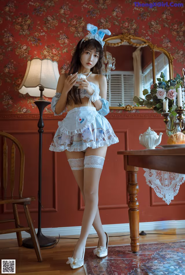 A woman in a white dress and white stockings posing for a picture.