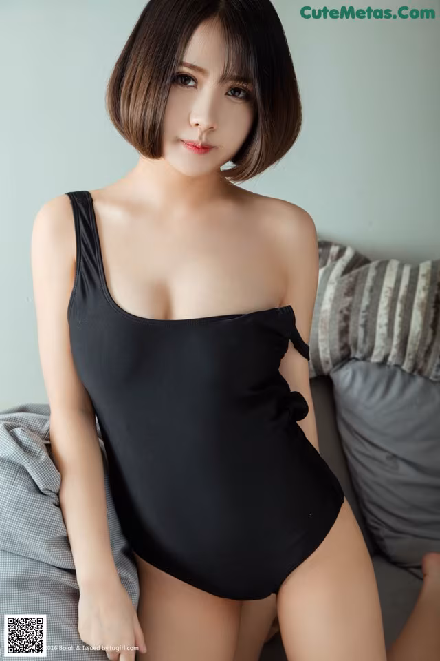 A woman in a black bathing suit sitting on a couch.