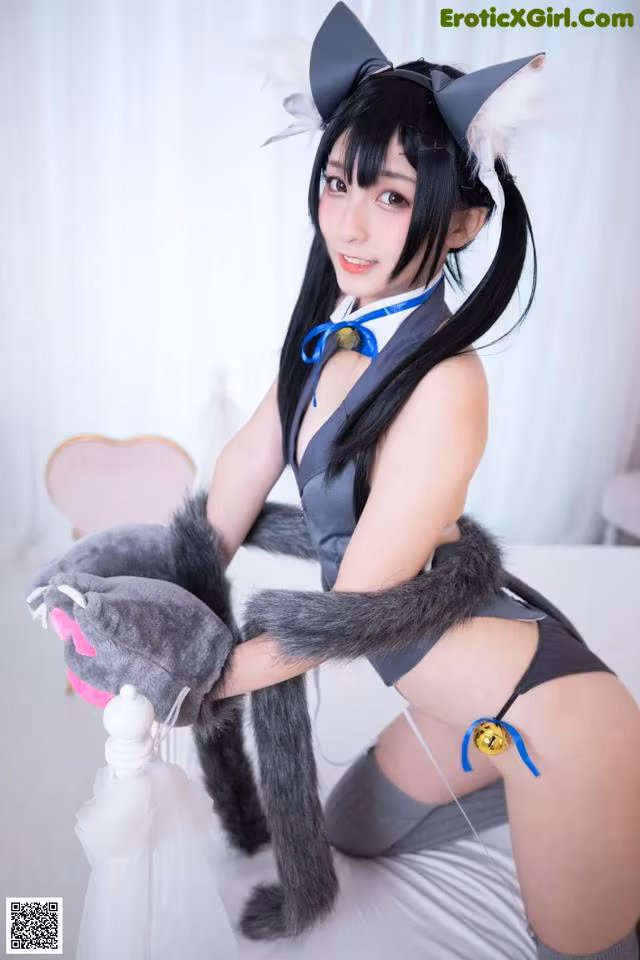 A woman in a cat costume holding a stuffed animal.