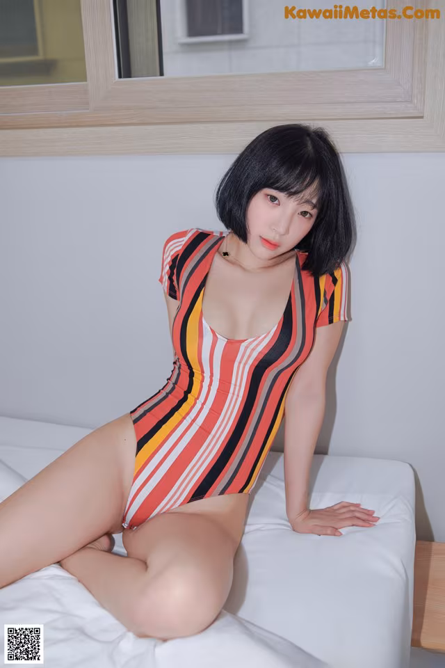 A woman in a striped bathing suit sitting on a bed.