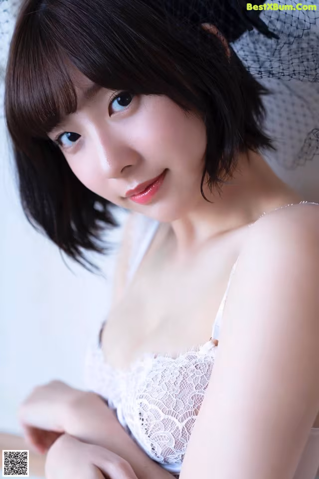 A woman wearing a white bra and a black hat.