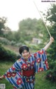 A woman in a blue and red kimono holding a stick.