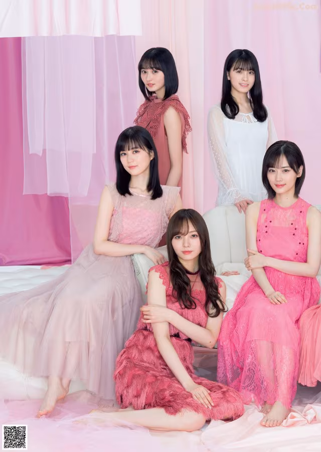 A group of young women sitting on top of a bed.