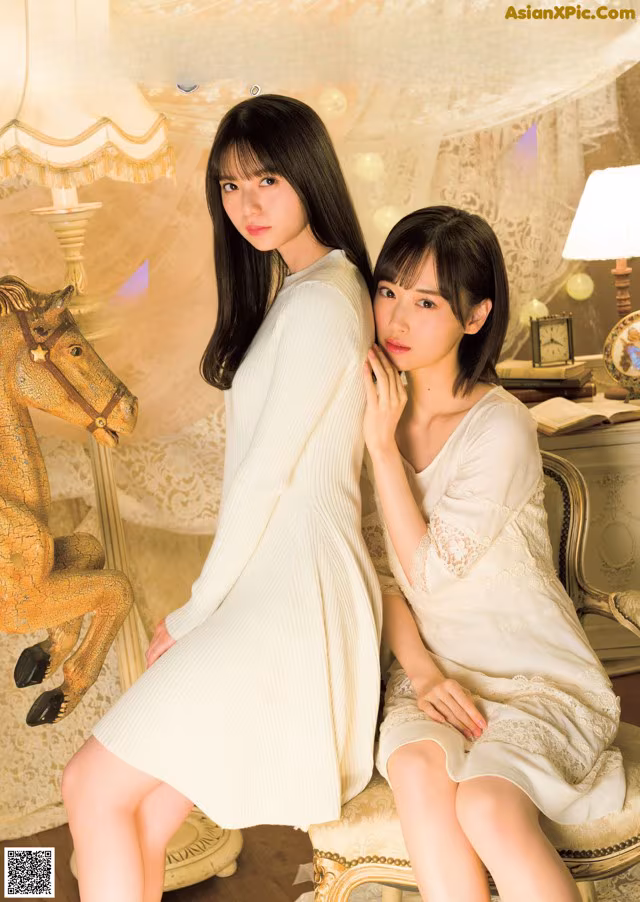 A couple of women sitting next to each other on a chair.