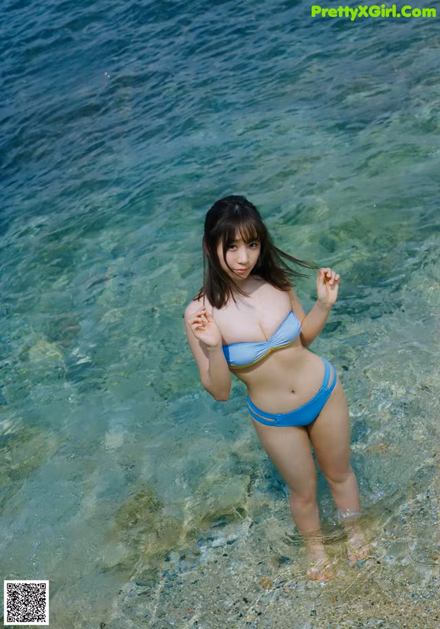 A woman in a blue bikini standing in the water.