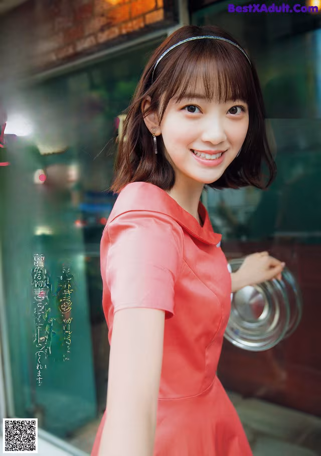 A woman in a pink dress standing in front of a store.