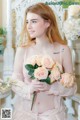 A woman in a pink dress holding a bouquet of flowers.