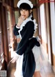 A woman dressed in a maid outfit posing for a picture.