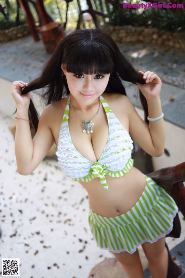 A woman in a green and white bikini posing for a picture.