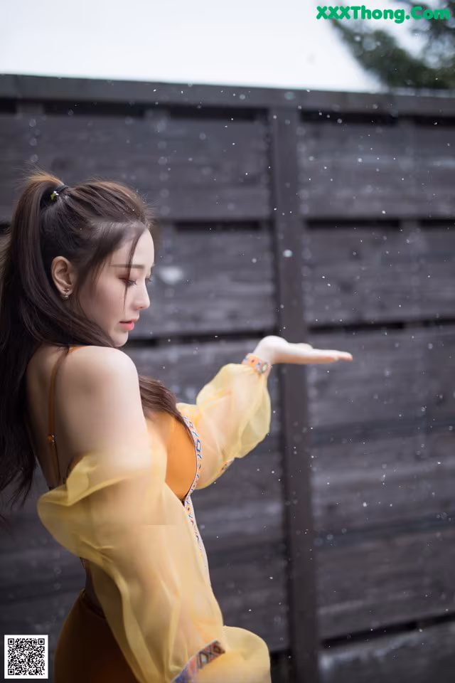 A woman in a yellow dress standing in the rain.