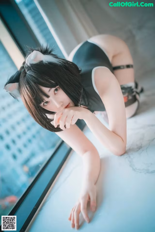 A woman in a cat costume leaning on a window sill.